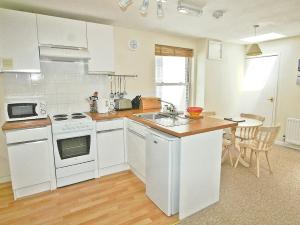 a kitchen with white appliances and a wooden floor at Poppy - 28865 in Stokeinteignhead