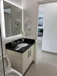 a bathroom with a sink and a mirror and a toilet at Torre EME Department in Mazatlán