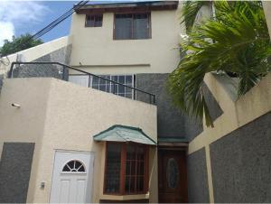 a white building with a door and a palm tree at Pearl of the City in Kingston