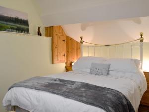 a bedroom with a large bed with white sheets at Caeberllan in Llanfair Caereinion