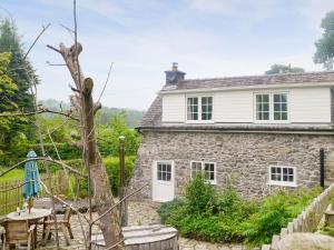 a stone cottage with a table and chairs in front of it at Caeberllan in Llanfair Caereinion