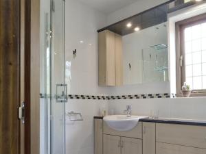 a white bathroom with a sink and a shower at Railway Cottage in Brassington