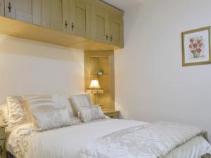a bedroom with a bed with white blankets and pillows at Railway Cottage in Brassington