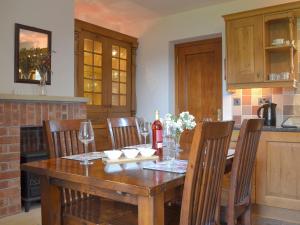 a kitchen with a wooden table with chairs and a bottle of wine at Railway Cottage in Brassington