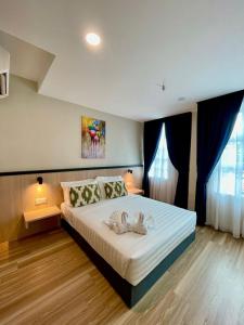 a bedroom with a large white bed with blue curtains at Savana Hotel & Serviced Apartments in Kuala Perlis