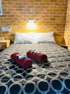 a bed with two pillows on it with a brick wall at Town and Country Motor Inn in Tamworth