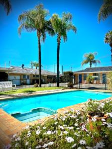 uma piscina em frente a uma casa com palmeiras em Town and Country Motor Inn em Tamworth