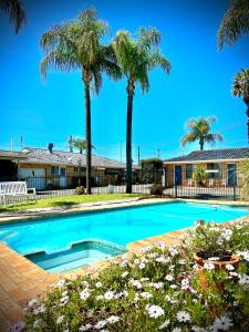 a swimming pool in front of a house with palm trees at Town and Country Motor Inn in Tamworth