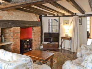 a living room with a brick fireplace and a tv at Tudor Cottage in Romsey