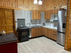 una cocina con armarios de madera y electrodomésticos de acero inoxidable en Cabaña rural límite con Argentina, en Futaleufú