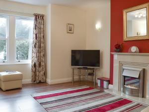 een woonkamer met een televisie en een open haard bij 3 Greta Grove House in Keswick