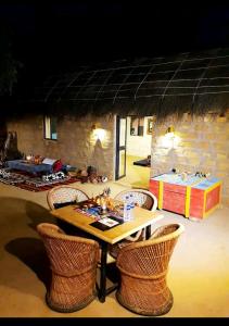 a table and chairs in a room with a stone wall at AnanyaVaas in Dedha