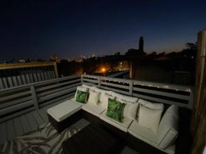 a white couch with two green pillows on a balcony at The Hidden Paradise Home Studio, Downtown City Views, Productions, Families & Large Groups in Baltimore