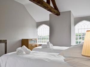 two white beds in a room with two windows at Old School House in Kirk Ireton