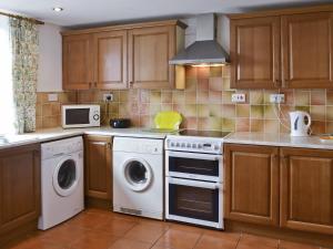 a kitchen with white appliances and wooden cabinets at Craneham Court in Buckland Brewer