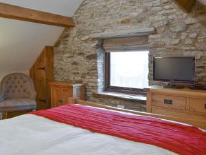 a bedroom with a large bed and a television at The Old Stable in Edale