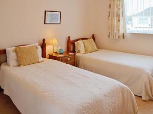 a bedroom with two beds and a table with a lamp at Goonlaze in St Austell