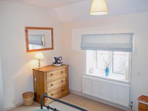 a bedroom with a dresser and a window at Cobble Stones in Holt