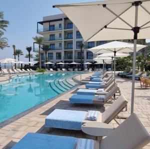 a pool with chairs and umbrellas next to a hotel at The Address Residence Fujairah in Fujairah