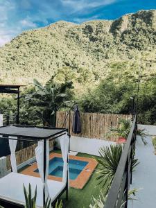 un patio con una mesa y una piscina con una montaña en Hideaway Cabins en Batangas