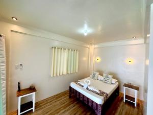 バタンガスにあるPamAnilao and Padoy's Dive Campの小さなベッドルーム(ベッド1台、テーブル2台付)
