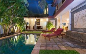 a house with a pool with a red chair next to it at 6BR Villa Sensel - Minggu Villas Seminyak in Seminyak