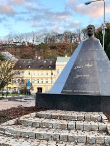 una estatua de un hombre sentado frente a un edificio en Hotel PAYER, en Teplice