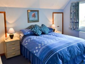 um quarto azul com uma cama com lençóis e almofadas azuis em The Wherry em Wroxham