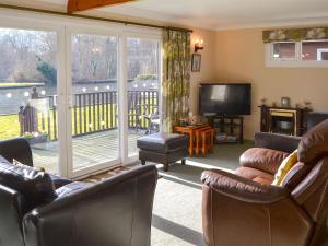 uma sala de estar com mobiliário de couro e uma televisão em The Wherry em Wroxham