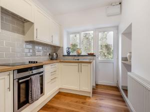 una cocina con armarios blancos y fregadero en 2 Cromwells Cottage-uk40929 en Pembroke