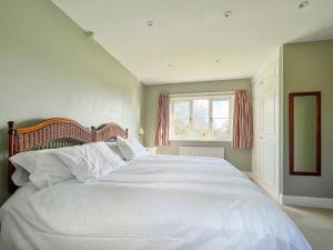 a large white bed in a bedroom with a window at Ladys Field House in Pensax