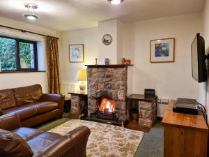 ein Wohnzimmer mit einem Sofa und einem Kamin in der Unterkunft Oakleigh Cottage in Llangelynin