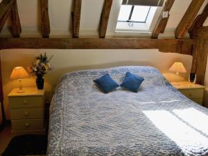 a bedroom with a bed with blue pillows and a window at Mount House Barn in Burwash