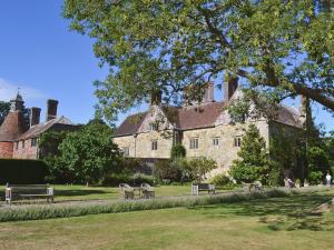 un gran edificio de piedra con bancos delante en Mount House Barn, en Burwash