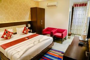 a bedroom with a large bed and a red chair at Hotel Taj Heights in Agra
