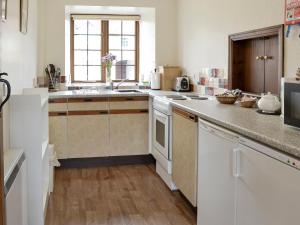 uma cozinha com armários brancos e uma bancada em Cow Pasture Cottage - Uk2297 em Ebberston