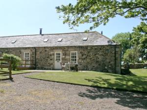 a stone barn with a table and chairs in front of it at Beach View in Bamburgh