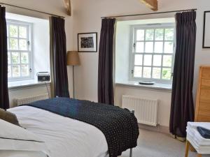 a bedroom with a bed and two windows at Beach View in Bamburgh