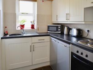 a kitchen with white cabinets and a black counter top at Smittergill in Ousby
