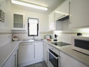 a white kitchen with white cabinets and a sink at Pine View - E5473 in Cromer