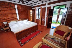 1 dormitorio con 1 cama grande en una habitación de ladrillo en The Lake by Maat Hotels, en Alleppey