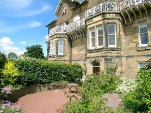 a large stone building with a balcony on top of it at Prudhoe Mews in Alnmouth