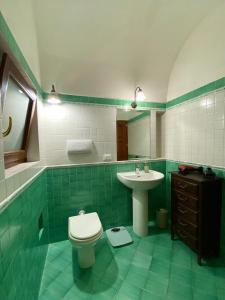 a green tiled bathroom with a toilet and a sink at Mina' Alfarah in Pantelleria