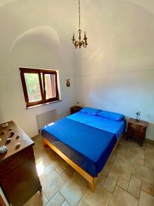 a bedroom with a blue bed and a chandelier at Mina' Alfarah in Pantelleria