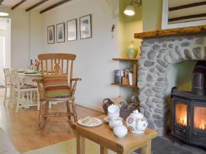 a living room with a fireplace and a chair and a table at Bryn Heulog in Penclawdd