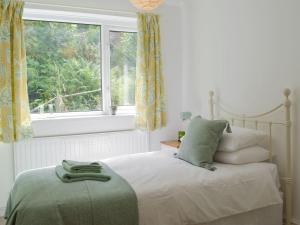 a white bedroom with a bed with a window at Bryn Heulog in Penclawdd