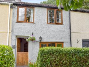 a white house with wooden windows and a door at Bryn Heulog in Penclawdd