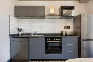 a kitchen with stainless steel appliances and gray cabinets at Manhattan On Coral Apartments in Bloubergstrand