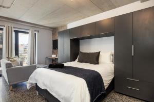 1 dormitorio con 1 cama grande y 1 silla en Manhattan On Coral Apartments, en Bloubergstrand