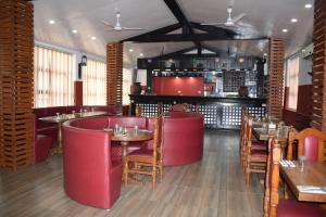 Hotel New Era في Butwāl: مطعم فيه كراسي حمراء وطاولات وبار
